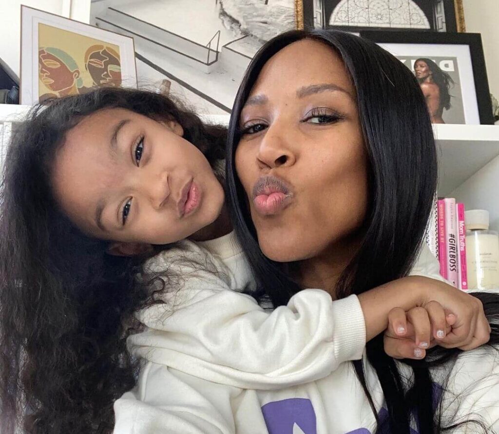An adult and a child with long hair pose for a selfie