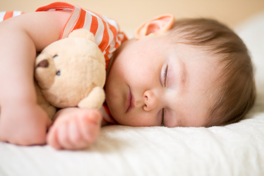 sleeping newborn baby on with a teddy