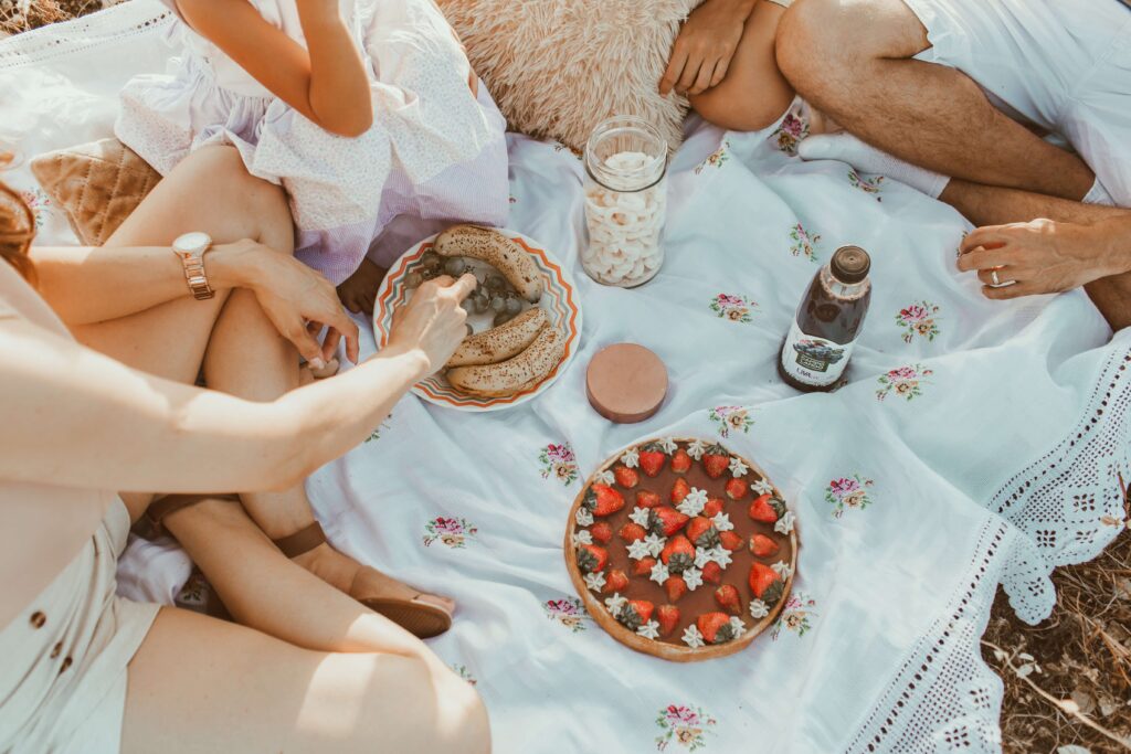 Three people having a picnic on a floral blanket