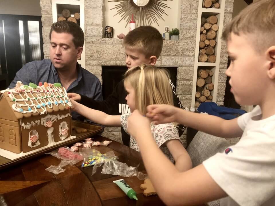 Family time with three children building a gingerbread house