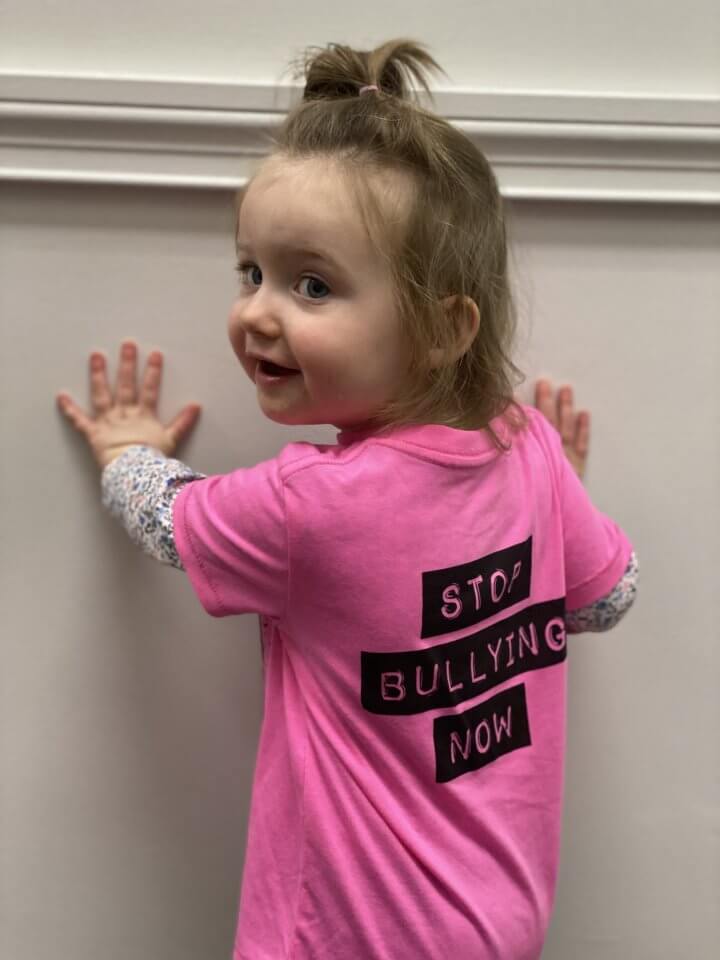 Child wearing a "Stop bullying now" shirt for pink shirt day