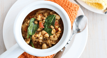 Bean and barley stew in a white fish with an orange napkin