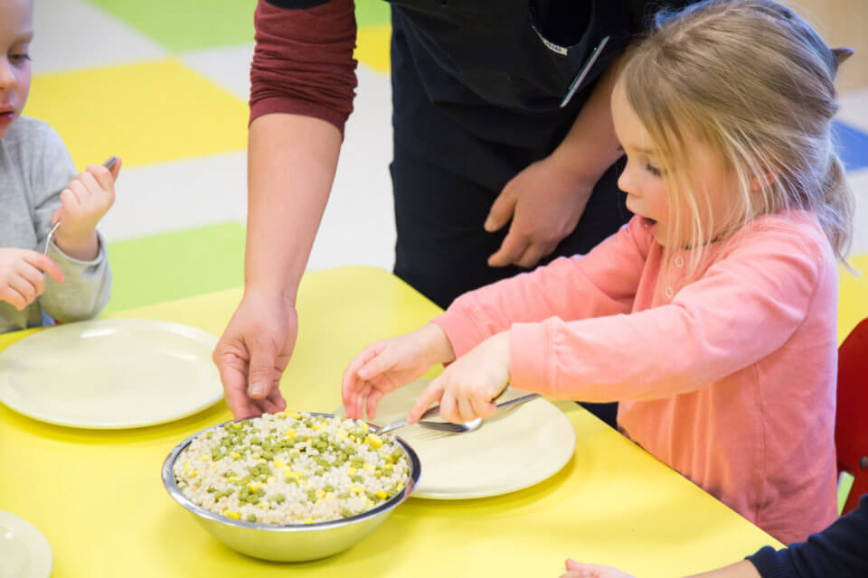 Child feeding herself engaged in family style dining