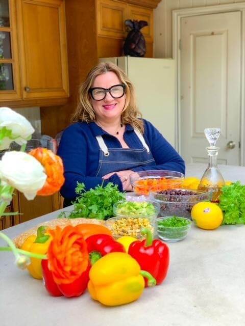 Chef lisa standing outside with vegetables and fruit