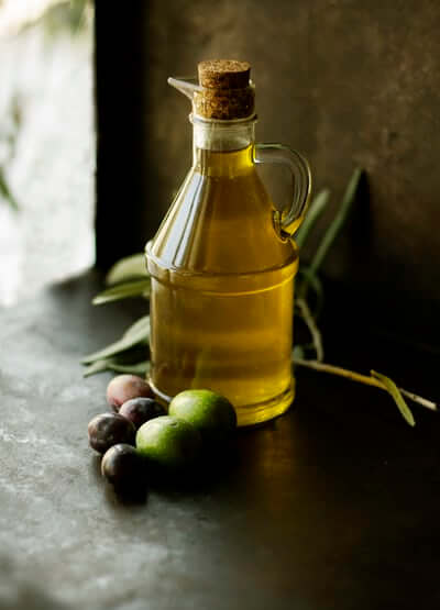 Bottle of olive oil with olives beside