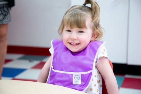 Toddler smiling with Kids and Company bib