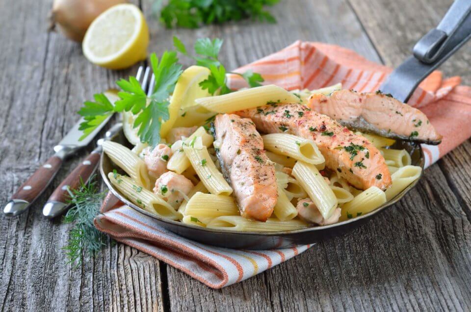 Salmon pasta on a wood table with lemon