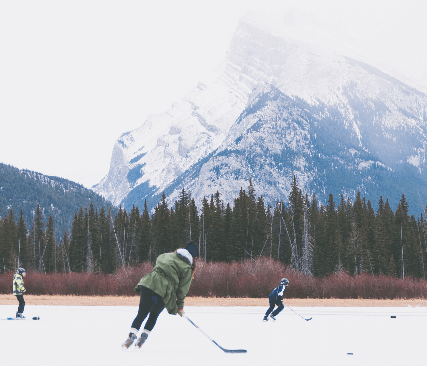 Family playing hockey on mountain lake