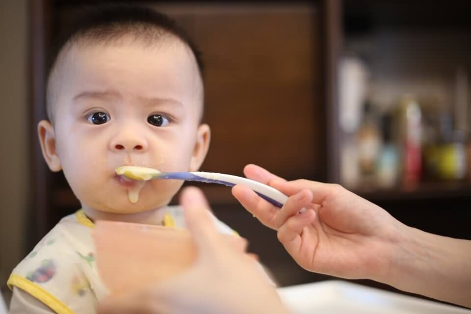 Baby getting fed wearing a yellow bib