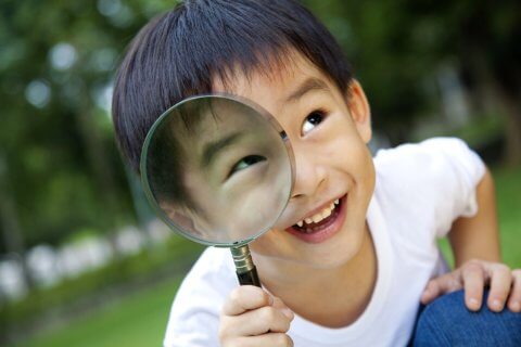 Child looking through magnifying glass