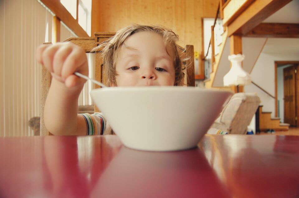 Child sitting at a table eating breakfast