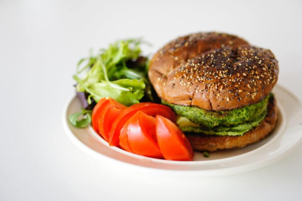 Veggie burger with salad on the side of a white plate