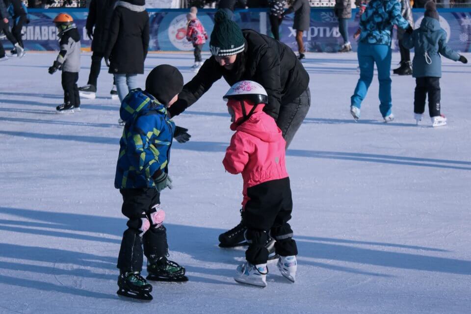 Two children on skates with an adult