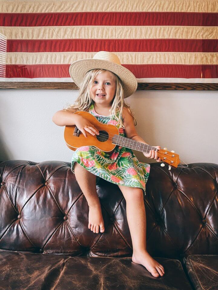 Child playing the guitar on a couch