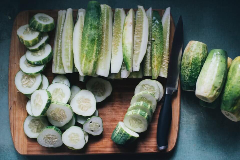 Cut up cucumbers on wooden board, perfect for kids by Kidco Kitchen