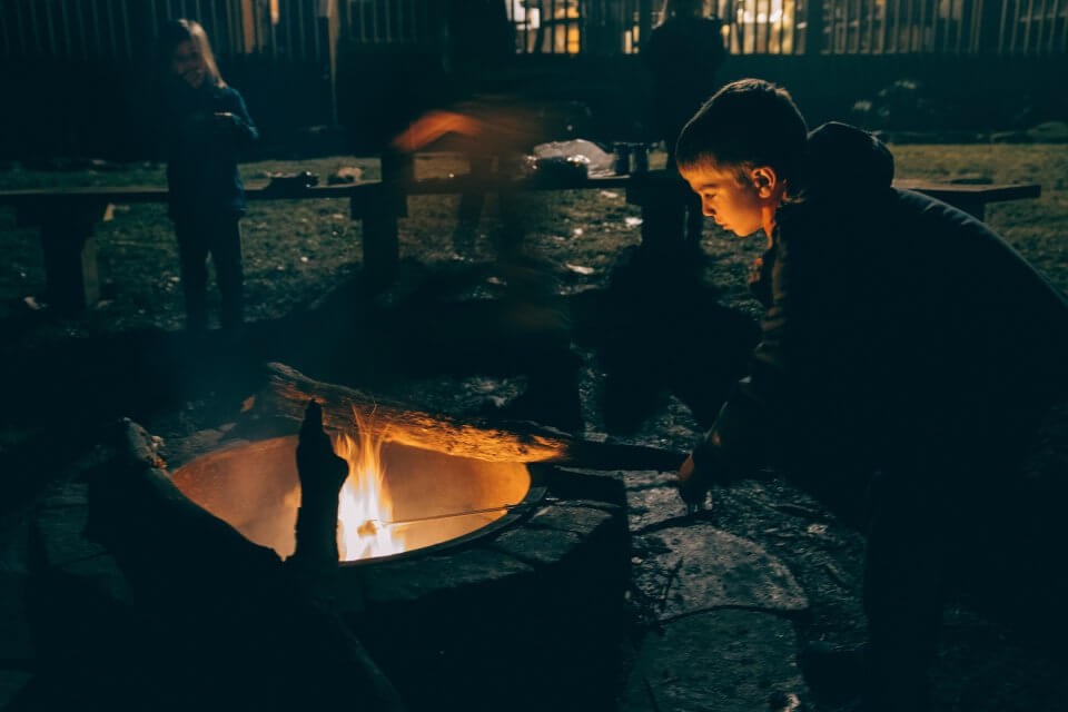 Boy outside by a fire in a winter coat