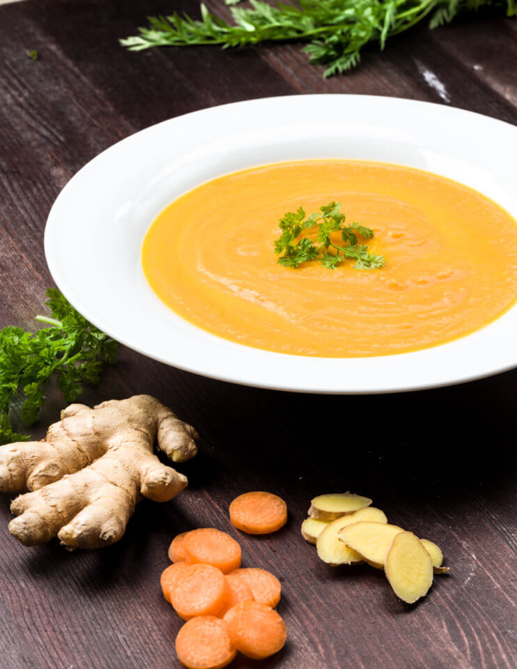 Ginger carrot soup in a white bowl on a wooden table