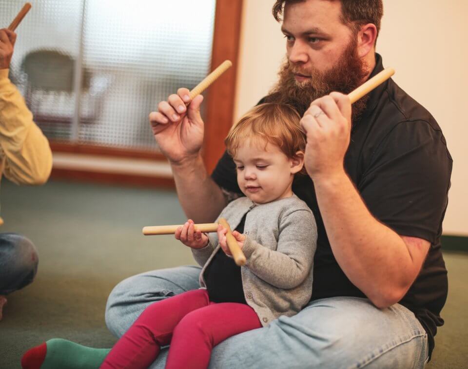 Child and father playing music together.