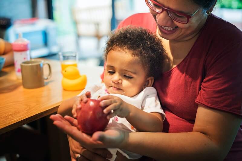 Mother and child sitting together holding an apple