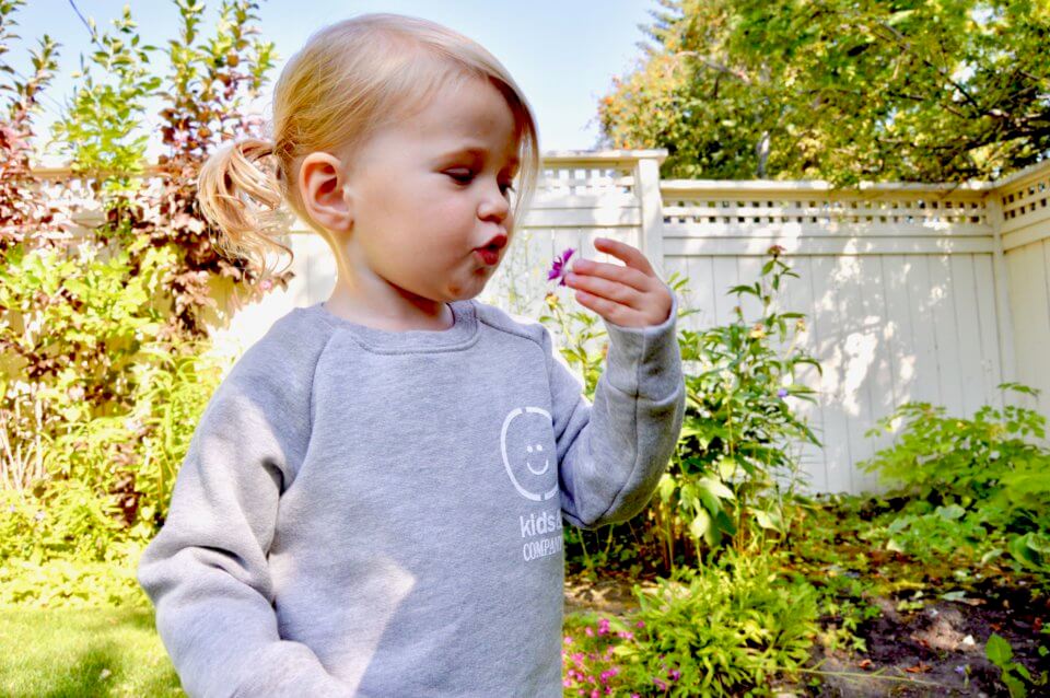 Girl outdoors looking at a flower