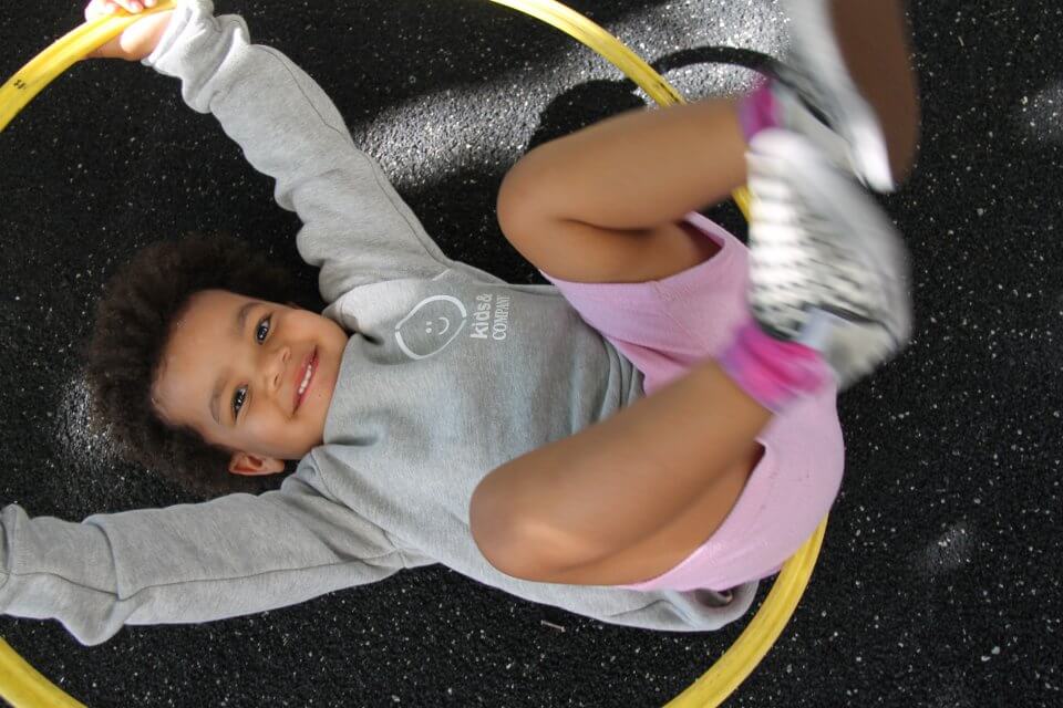 Child laying on the ground with a hoola hoop