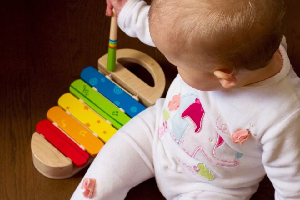Child sitting on the floor playing a colourful instrument