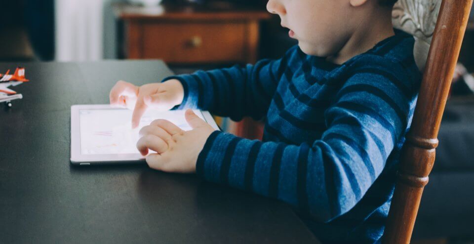 child playing with an ipad at the dinner table