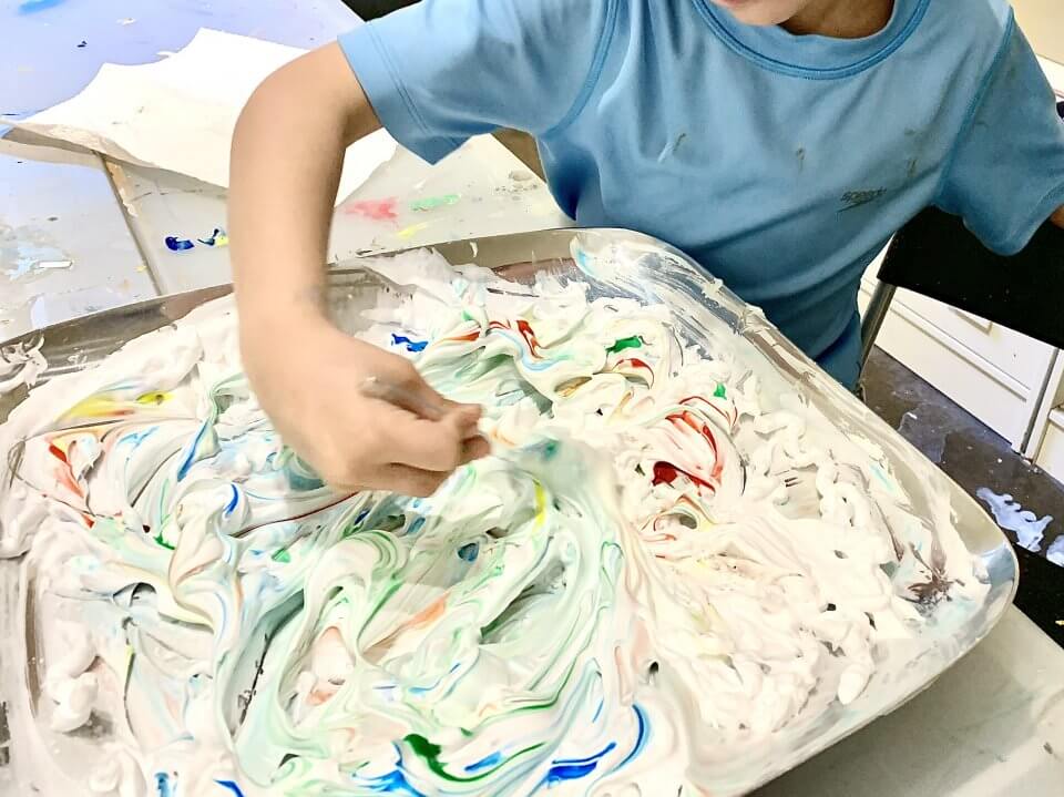 Child doing a shaving cream painting at home.