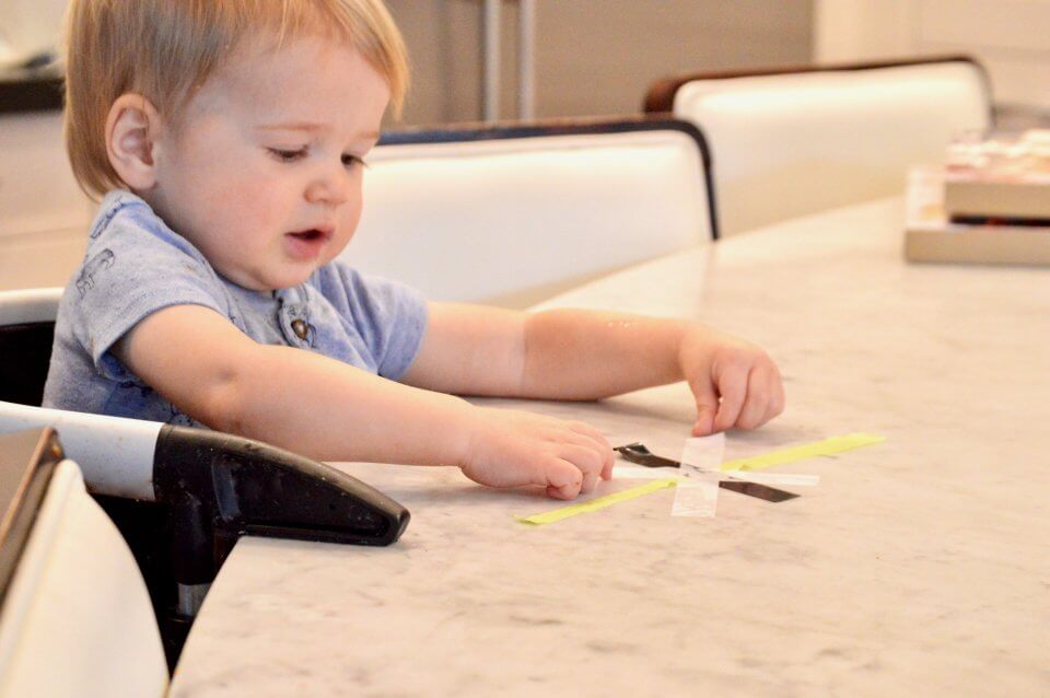 A child is playing with tape, making outlines of a star.