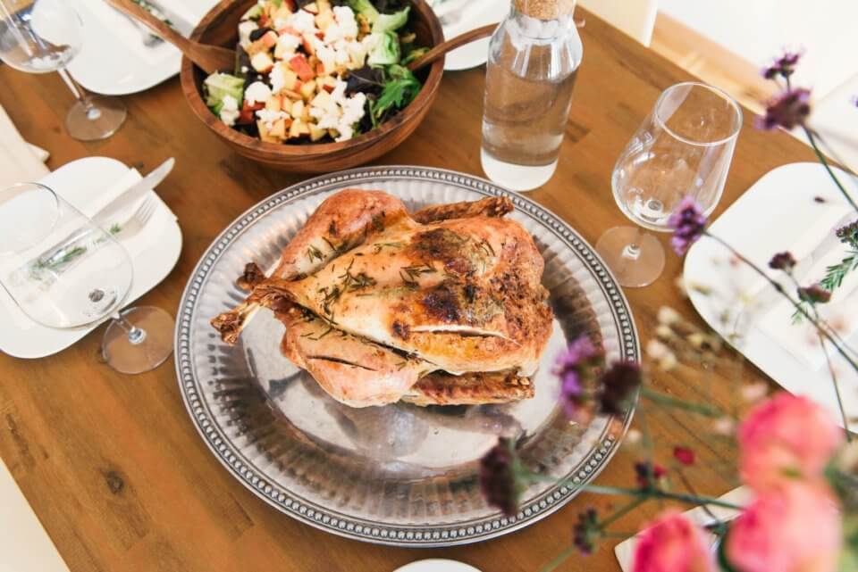 Turkey on a silver platter surrounded by flowers and salad.