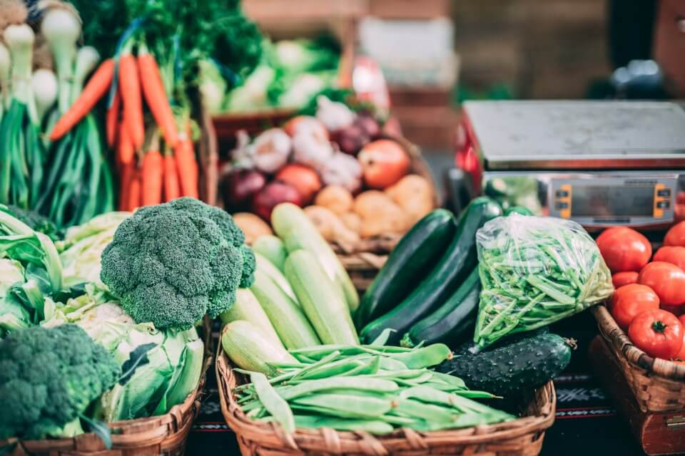 Variety of green vegetables, carrots, onions and tomatoes at the grocery store