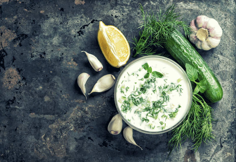 Tzatziki, lemon, cucumber and garlic on grey table